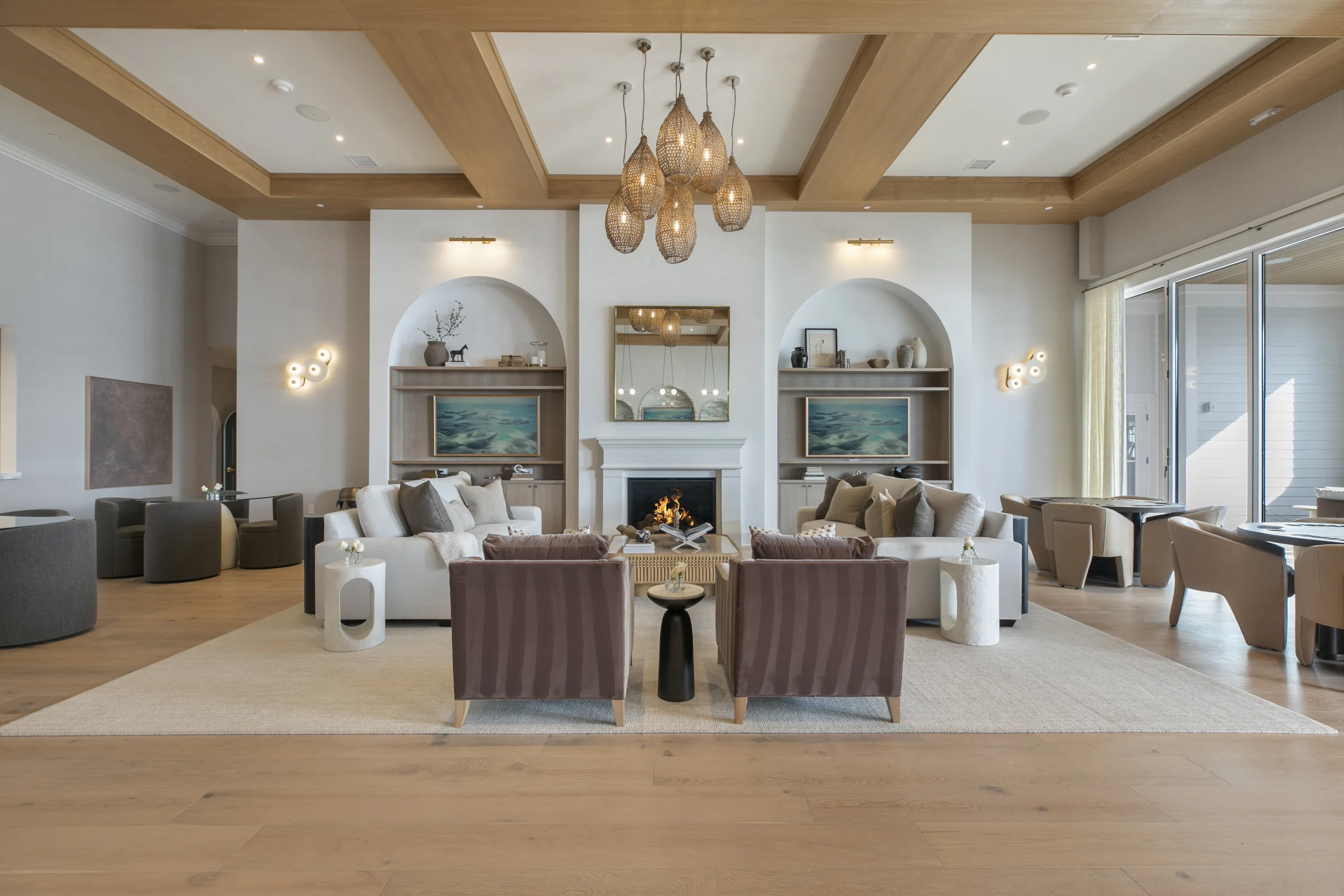 Symmetrical great room seating around a fireplace, flanked by arched built-ins under a woven pendant chandelier