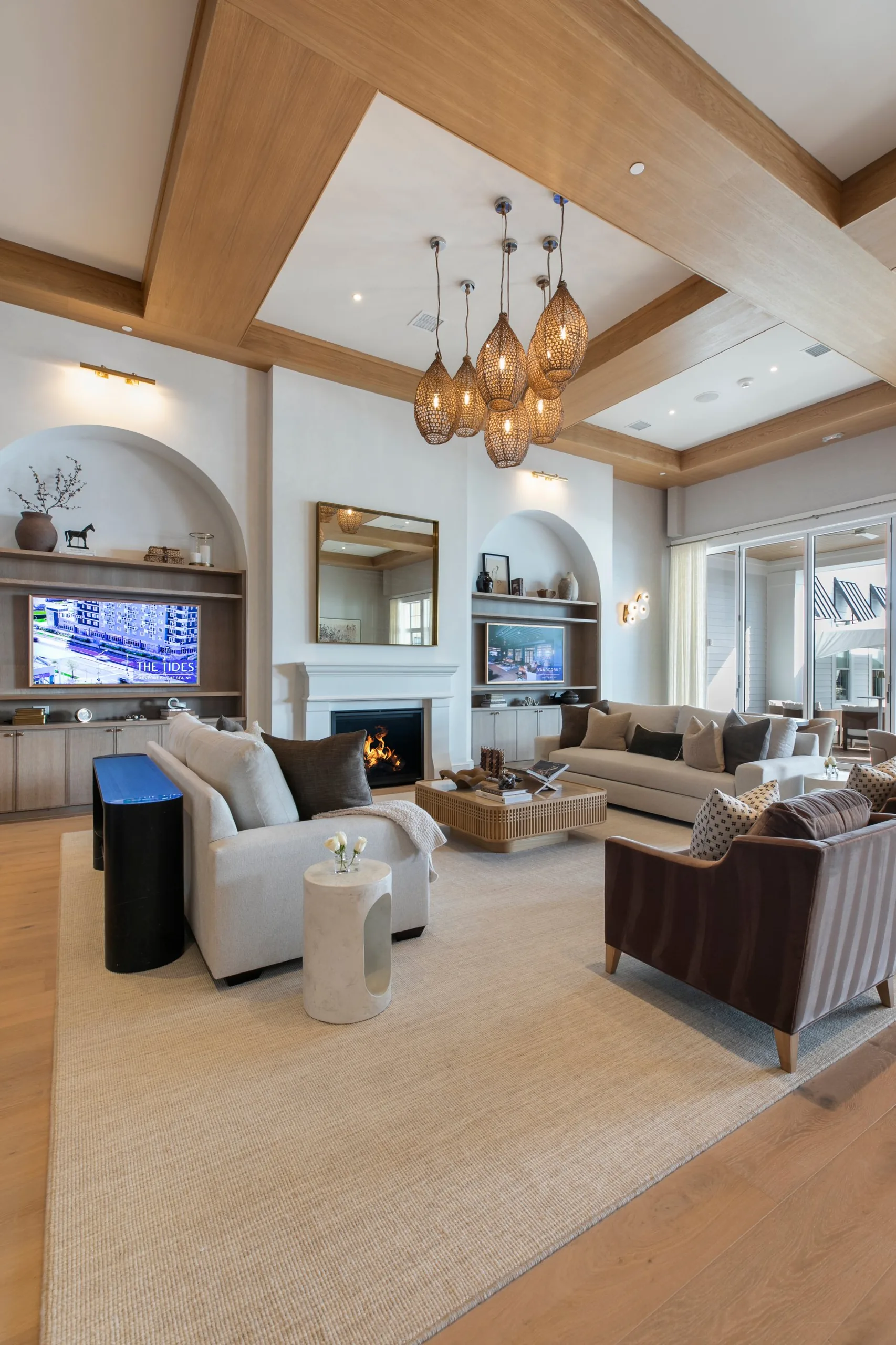 Great room with a fireplace, arched built-in shelving, wood-beamed ceiling, woven pendant chandelier and plush seating