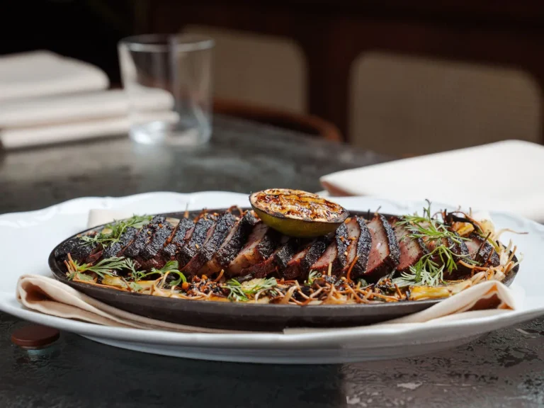 Sliced, char-crusted duck on a cast iron platter at The Comet Club in Westbury