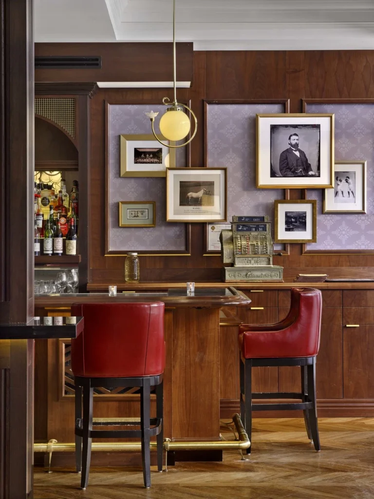 Interior bar seating at Morrissey's Lounge & Bistro with red leather barstools, vintage photographs, and wood paneling