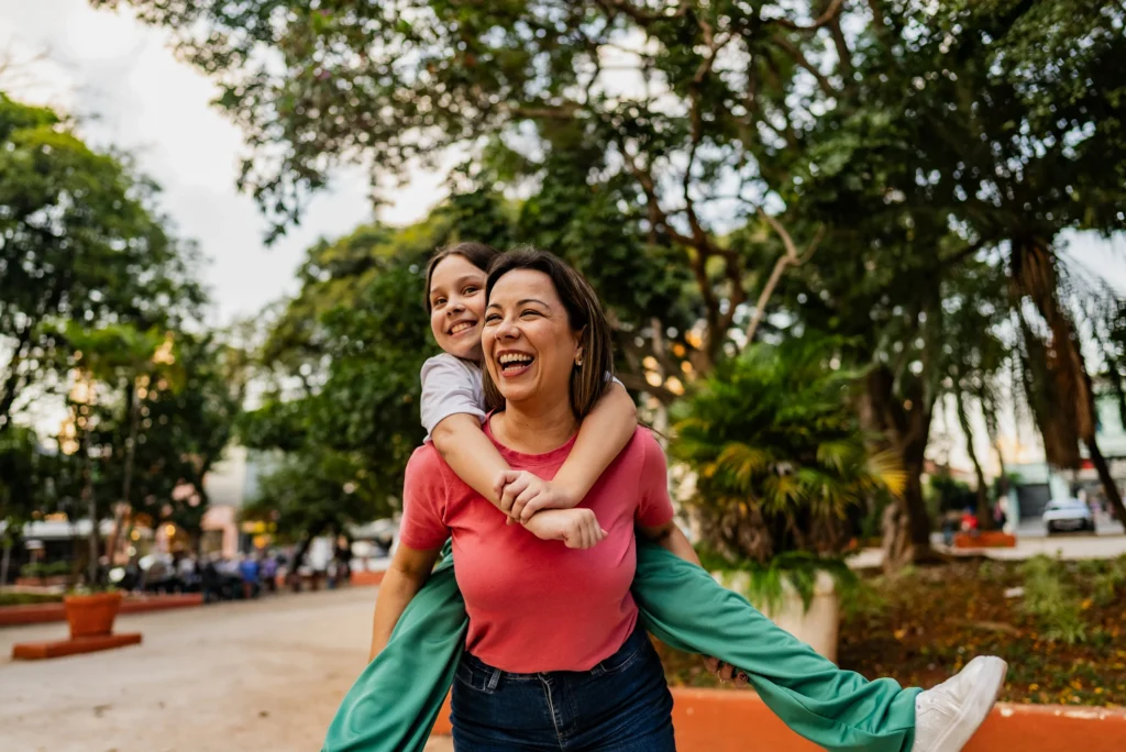 Mother and daughter piggyback outdoors